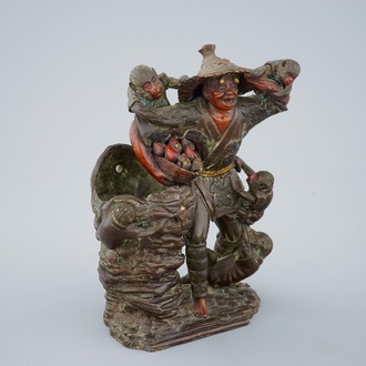 Een Japanse terracotta okimono van een fruitverkoper met apen, Edo/Meiji, 18/19e eeuw