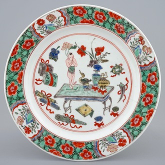 Een Chinees famille verte bord met een zotje op een tafel, Kangxi