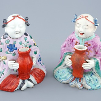 Een paar Chinese famille rose figuren van zittende jongens met een vaas, 18/19e eeuw