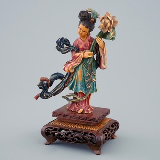 Een Chinese polychrome ivoren dame met bloem op houten sokkel, begin 20e eeuw