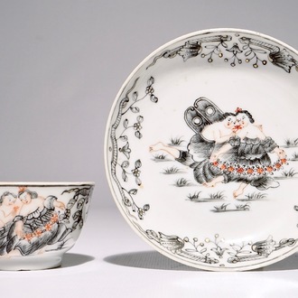 Een Chinese grisaille, vergulde en ijzerrode kop en schotel met romantisch decor, Qianlong