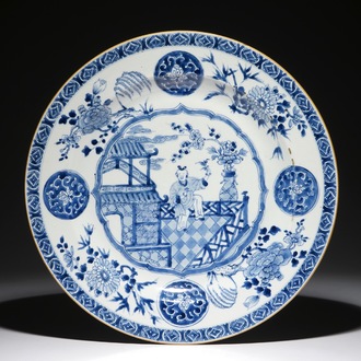 Een grote Chinese blauwwitte schotel met een zotje op een terras, Qianlong