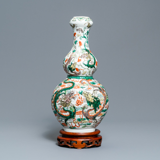 Een Chinese famille verte kalebasvaas met relëfdecor van draken op houten sokkel, 19/20e eeuw