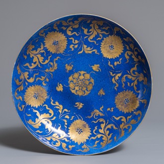 Een Chinese poederblauwe en vergulde schotel met floraal decor, Kangxi