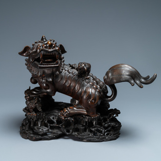 Een Chinees bronzen model van een boeddhistische leeuw op houten sokkel, 18e eeuw