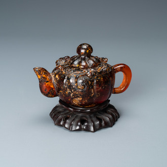 Een Chinese theepot in amber op houten 'lotus' sokkel, 19e eeuw