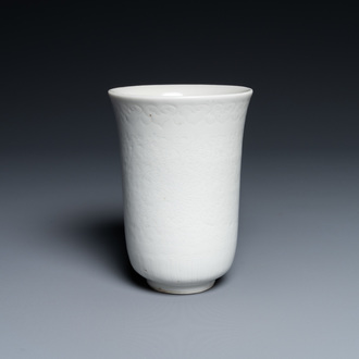 Een Chinese monochrome witte beker met anhua decor van pioenslingers, Xuande merk, Kangxi