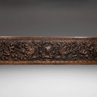 A sculptured walnut panel with putti, allegorical characters and human-headed dragons around an ecusson, presumably France, 16th C.