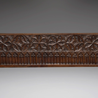 A carved front panel of a Gothic walnut chest with female saints, alcoves and rosettes, France, early 16th C.