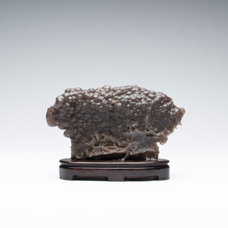 A Chinese grape agate scholar's rock on wooden stand, 20th C.