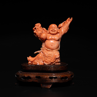 A Chinese red coral figure of a laughing Buddha on wooden stand, 19/20th C.