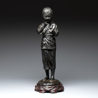 A Japanese bronze sculpture of a boy feeding a bird on a wooden stand, signed, Meiji, 19th C.