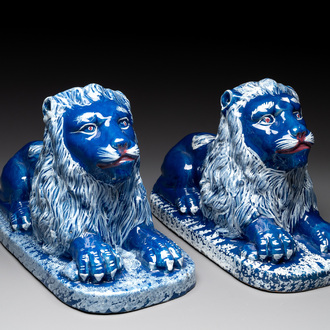 A pair of white-decorated blue-ground faience models of reclining lions, Nevers, 18th C.