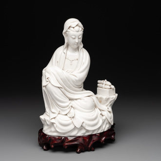 A Chinese Dehua blanc de Chine figure of a seated Guanyin on wooden stand, 19/20th C.