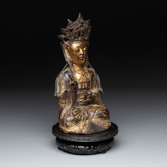 A Chinese parcel-gilt bronze Guanyin and wooden stand, Ming