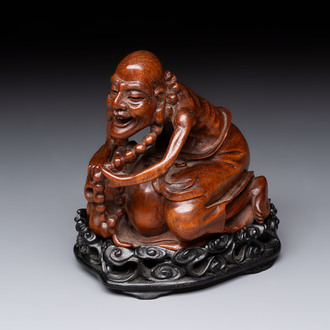 A Chinese fine huanghuali sculpture of a Luohan on a zitan stand, Qianlong mark, 19/20th C.