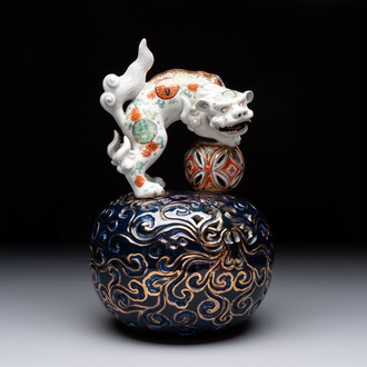 A Japanese Kutani group of a Shishi standing on an openworked brocade ball, 20th C.