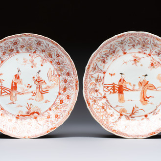 A pair of Chinese iron-red and gilt-decorated 'Elegant Beauties in a Garden' dishes, Kangxi