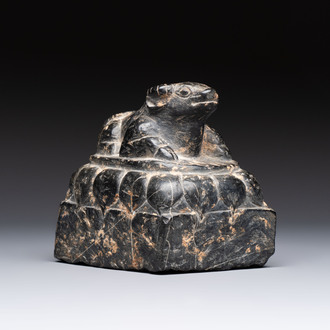 A Chinese carved black stone paper weight in the shape of a reclining buffalo on a lotus throne, Northern and Southern dynasties