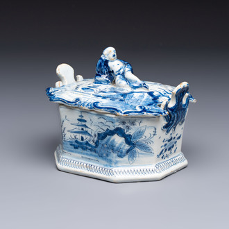 A blue and white Dutch Delft chinoiserie butter tub with a reclining figure finial, 18th C.