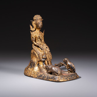 A Thai gilt-bronze figure of a seated deity with attendant animals, 19th C.
