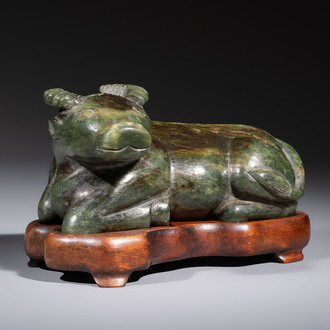 A Chinese green jade reclining buffalo on a wooden stand, 19/20th C.