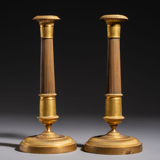 A pair of Empire parcel-gilt bronze candlesticks, early 19th C.