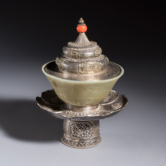 A Tibetan ritual jade bowl with a red coral-mounted silver cover and a stand, 19th C.