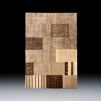 A large Persian hand-knotted woollen carpet with a geometric patchwork design, 20th C.