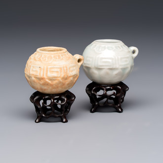 A pair of Chinese bird feeders with moulded design, one unglazed, on later wooden stands, Song