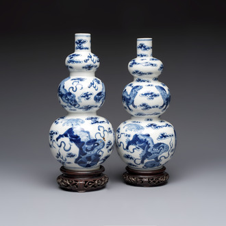 A pair of Chinese blue and white 'Buddhist Lions' triple gourd vases on reticulated wooden stands, 19th C.