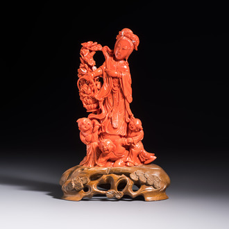 A Chinese carved red coral 'Goddess and Boys' group on a wooden stand, 19/20th C.