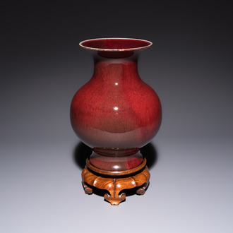 A Chinese copper-red-glazed vase on a wooden stand, 20th C.