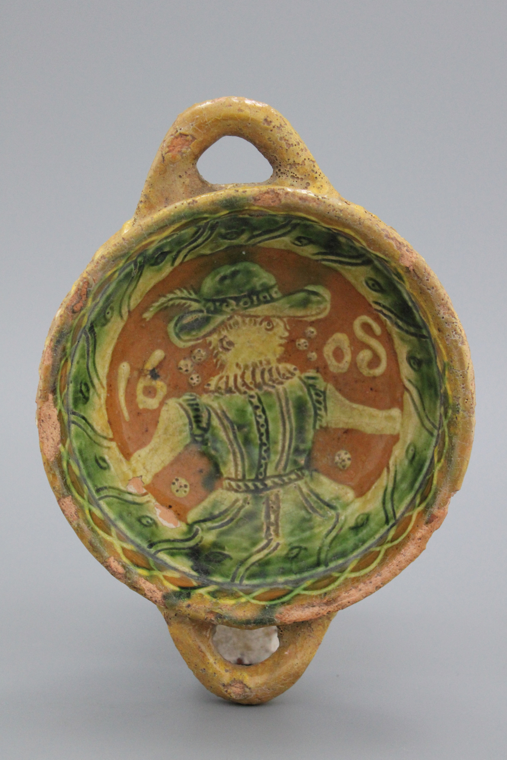 A Dutch slipware decorated porringer with a figure, dated 1608