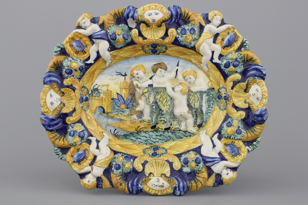 A relief-moulded polychrome oval dish with putti dehorning a goat, 18/19th C.