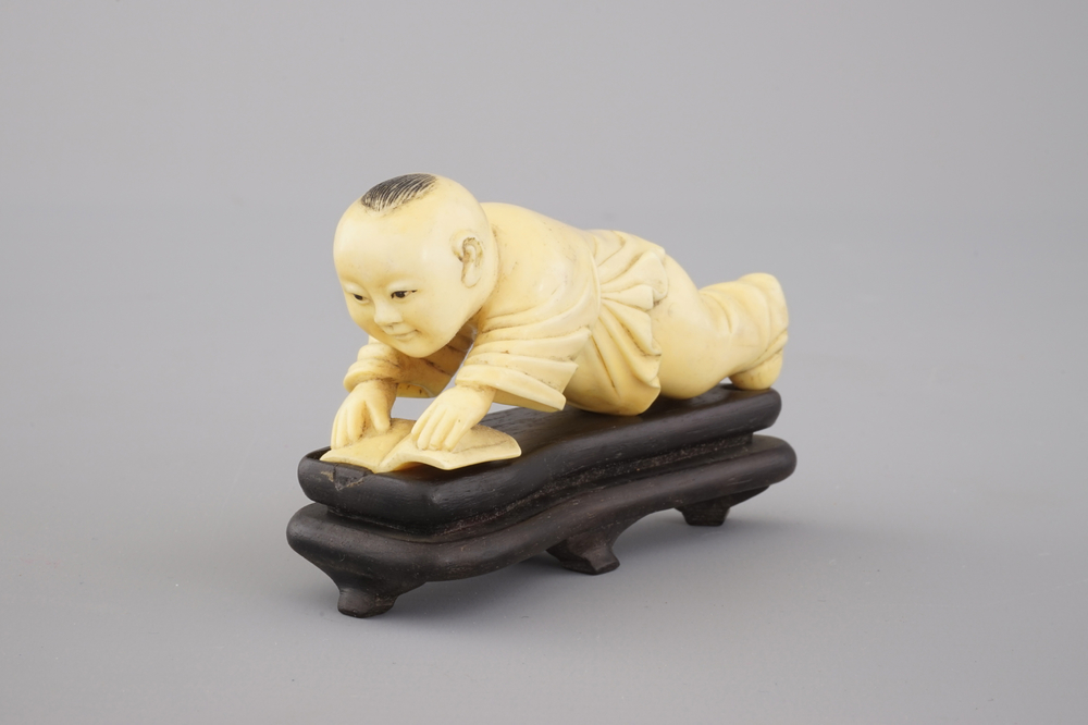 A Chinese carved ivory figure of a boy reading a book, 19/20th C.