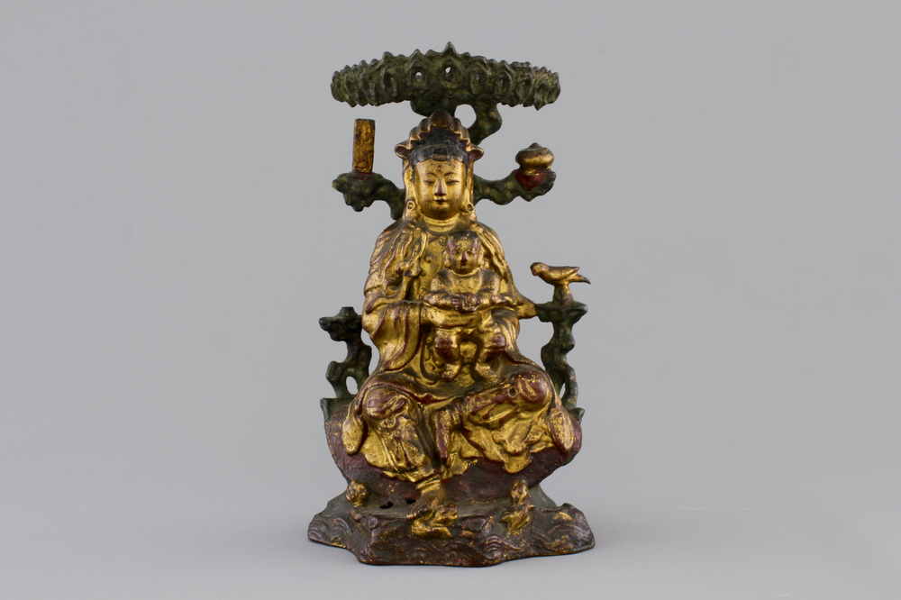 A Chinese bronze and gilt Buddha with child, seated beneath a bodhi tree, 17/18th C.