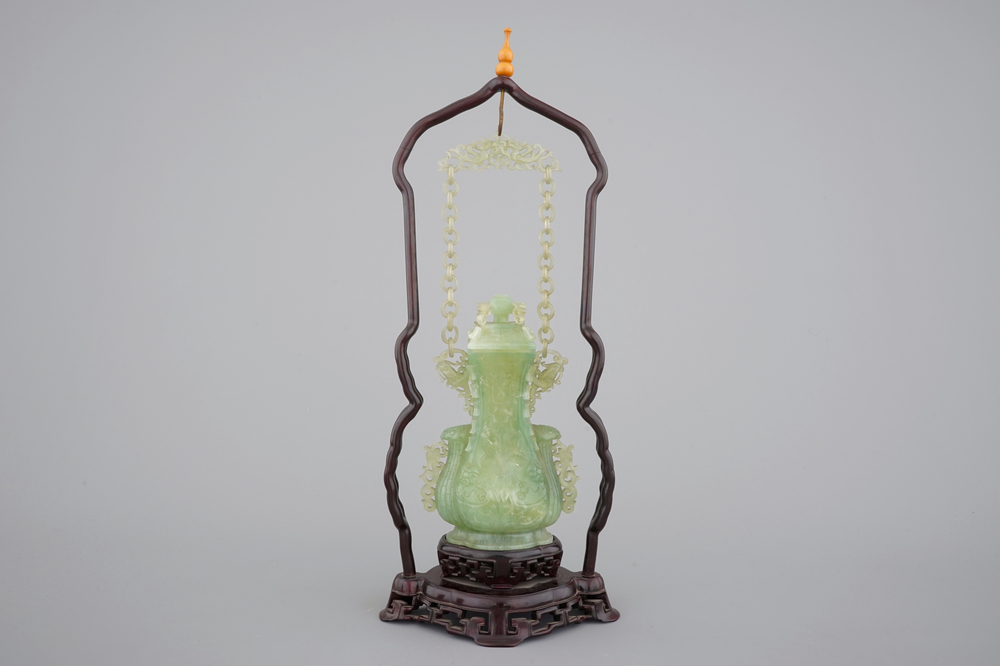 A Chinese carved green jadeite vase and cover on elaborate wooden stand, 19/20th C.
