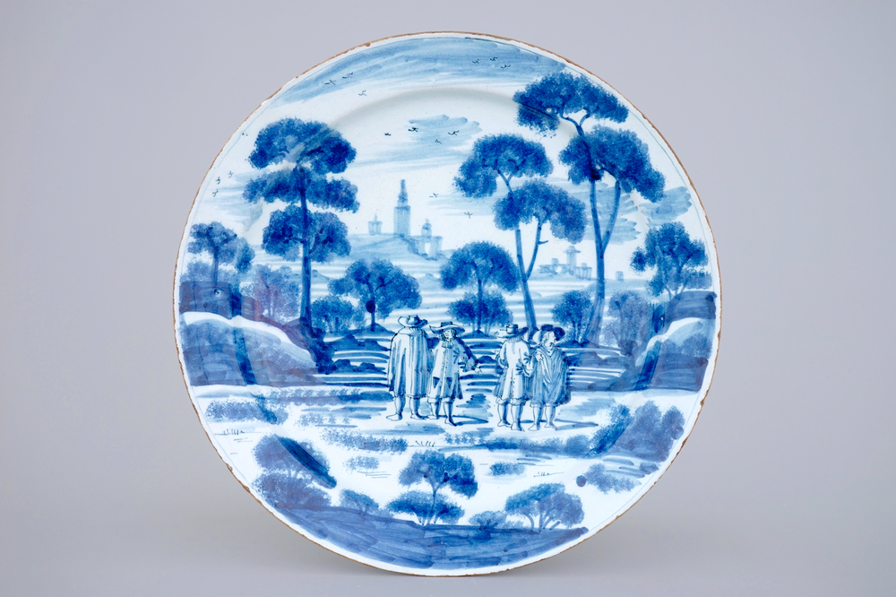 A large Dutch Delft blue and white dish with noblemen in a landscape setting, 18th C.