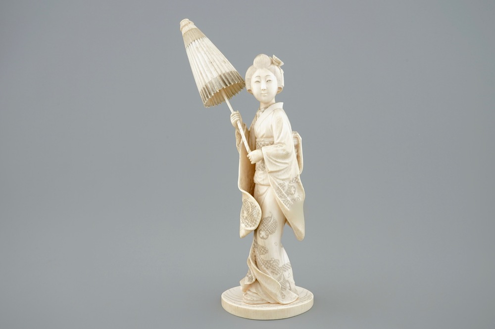 Een Japanse ivoren okimono, dame met parasol, 19e eeuw