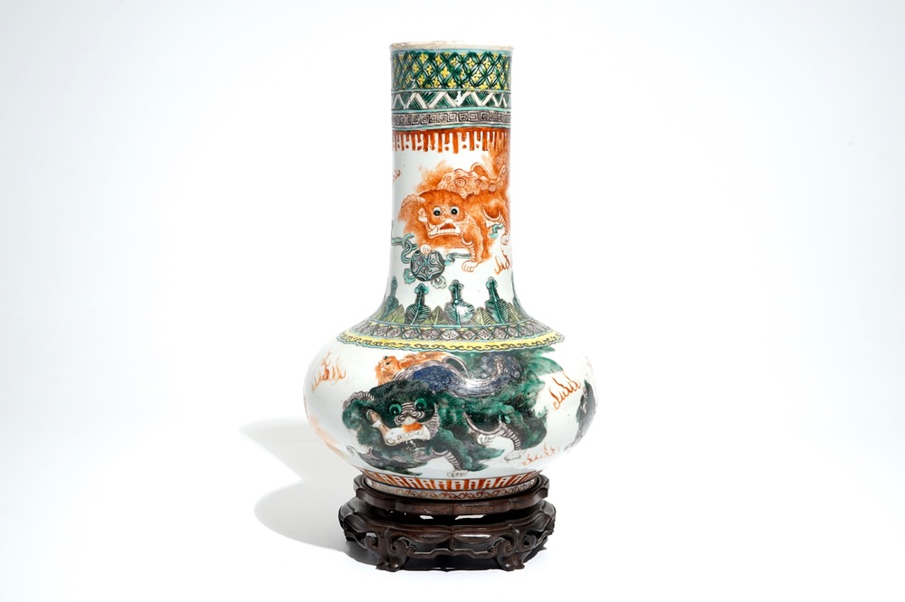 A Chinese famille verte vase with Buddhist lions on wooden stand, 19th C.