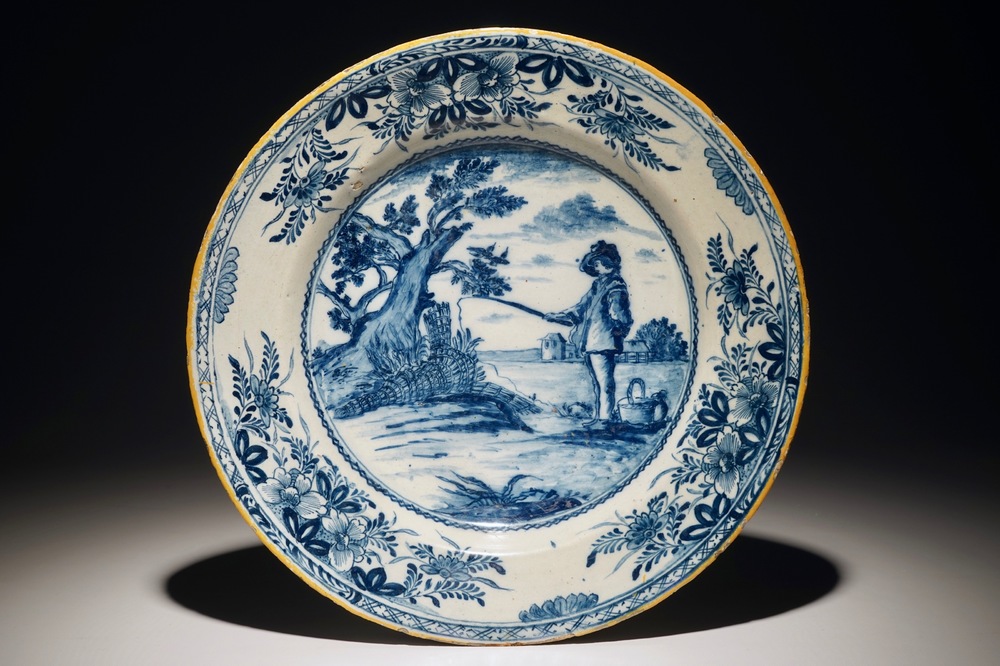 Un plat en fa&iuml;ence de Delft bleu et blanc figurant "Le jeune p&ecirc;cheur" d'apr&egrave;s Bloemaert, 18&egrave;me
