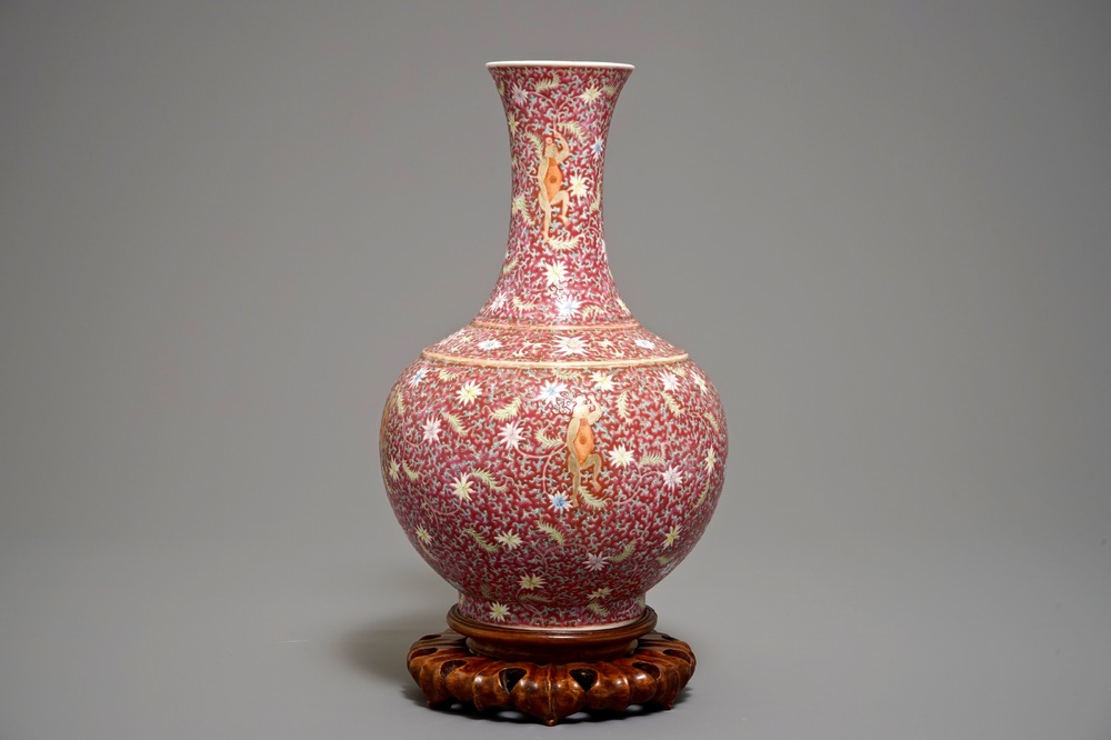 A Chinese ruby-ground famille rose bottle vase with dancing boys, Qianlong mark, 19/20th C.