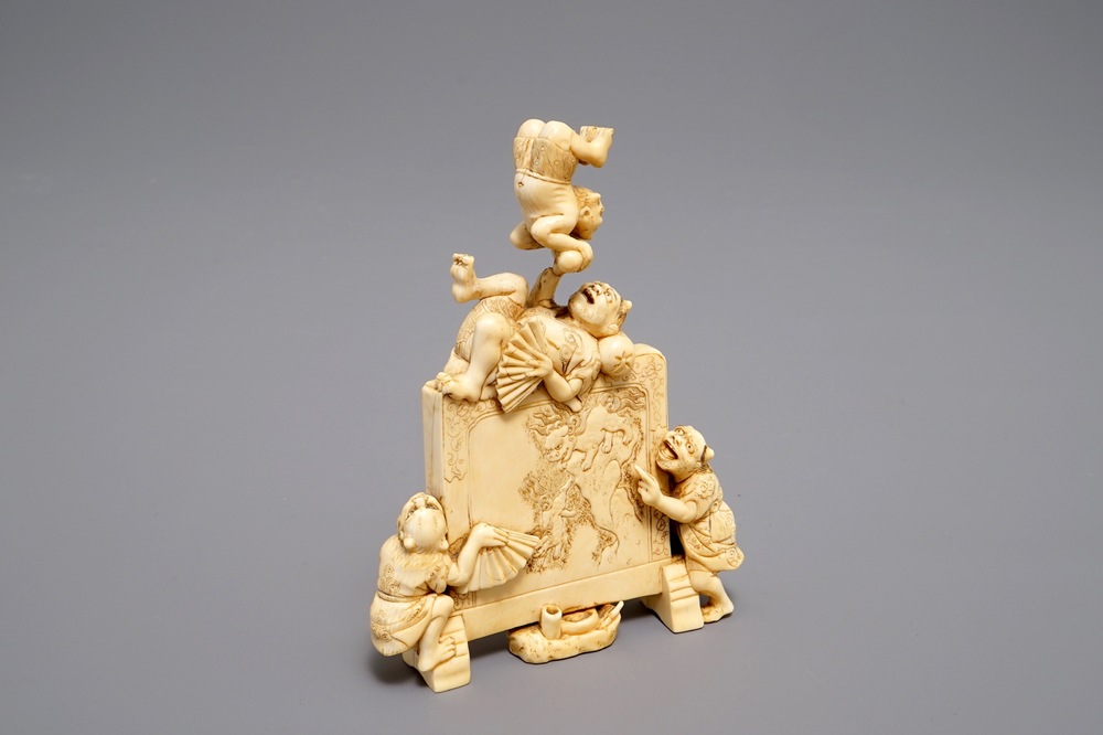 A Japanese carved ivory okimono with oni around a screen, signed, Meiji, 19th C.