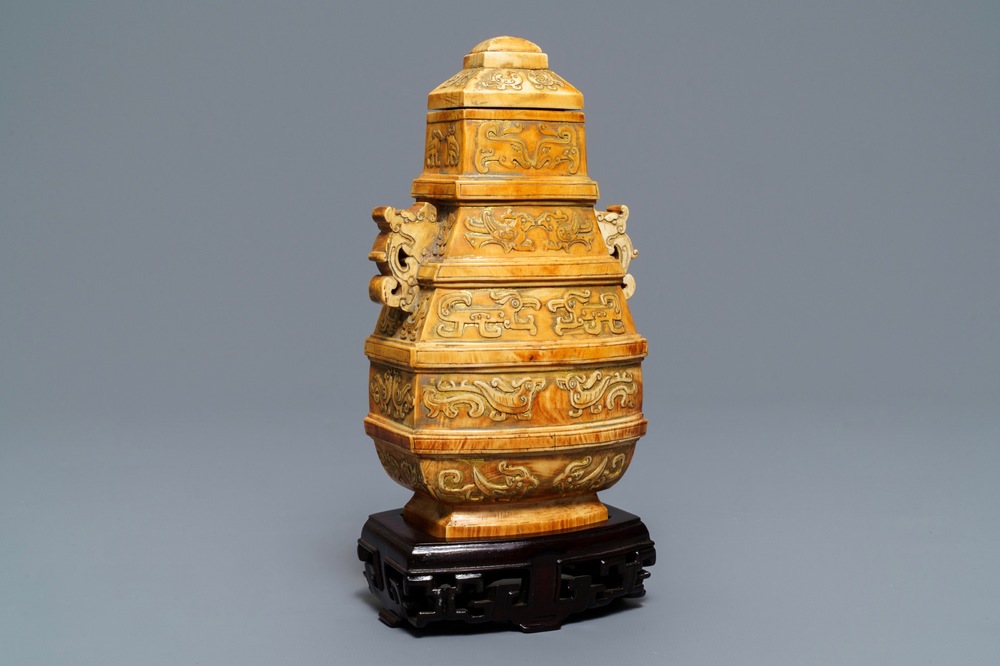 A Chinese archaistic ivory vase and cover on wooden stand, ca. 1900