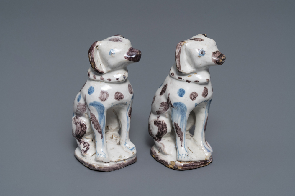 A pair of blue, white and manganese Brussels faience models of dogs, 18th C.