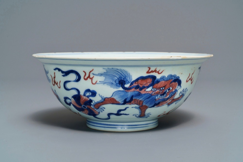 Een Chinese blauw-witte en onderglazuur rode kom met tempelleeuwen, Qianlong merk en periode