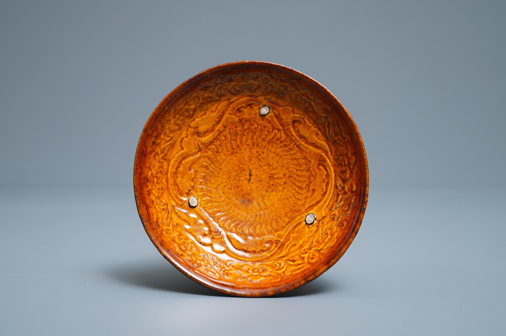 Une assiette en gr&egrave;s porcelaineux &agrave; couverte ambre &agrave; d&eacute;cor en relief, Liao (916-1125)
