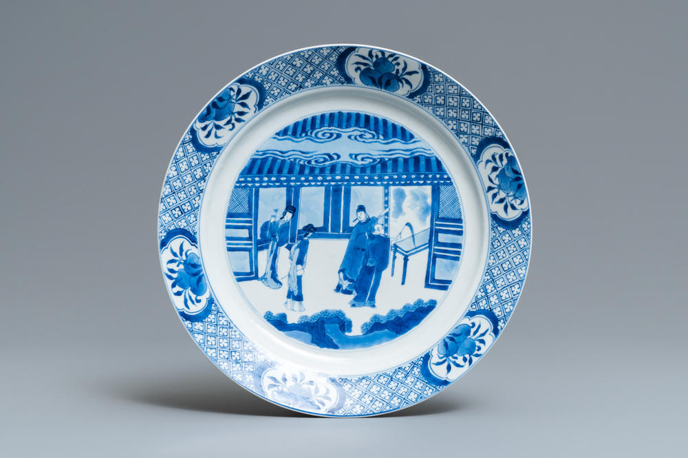 Un plat en porcelaine de Chine en bleu et blanc &agrave; d&eacute;cor de figures dans un int&eacute;rieur, marque et &eacute;poque de Kangxi