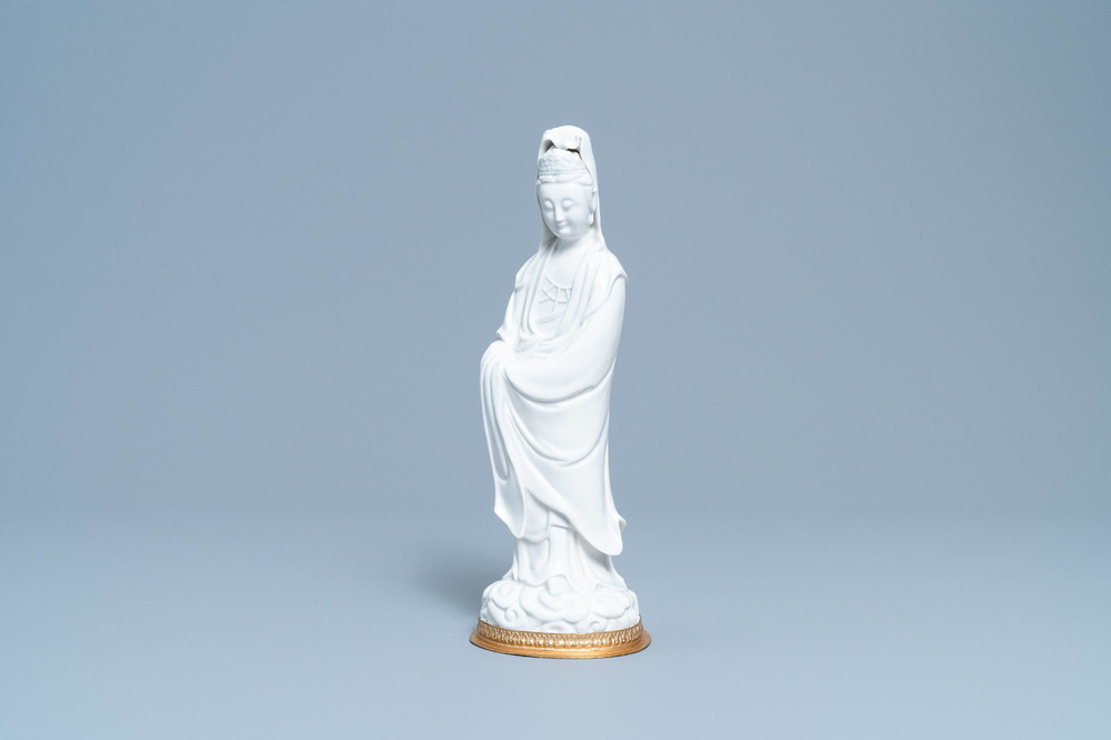 A Chinese blanc de Chine figure of Guanyin on a gilt bronze base, 18/19th C.